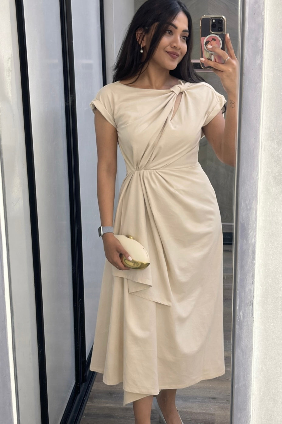 Woman taking a mirror selfie wearing a beige dress.