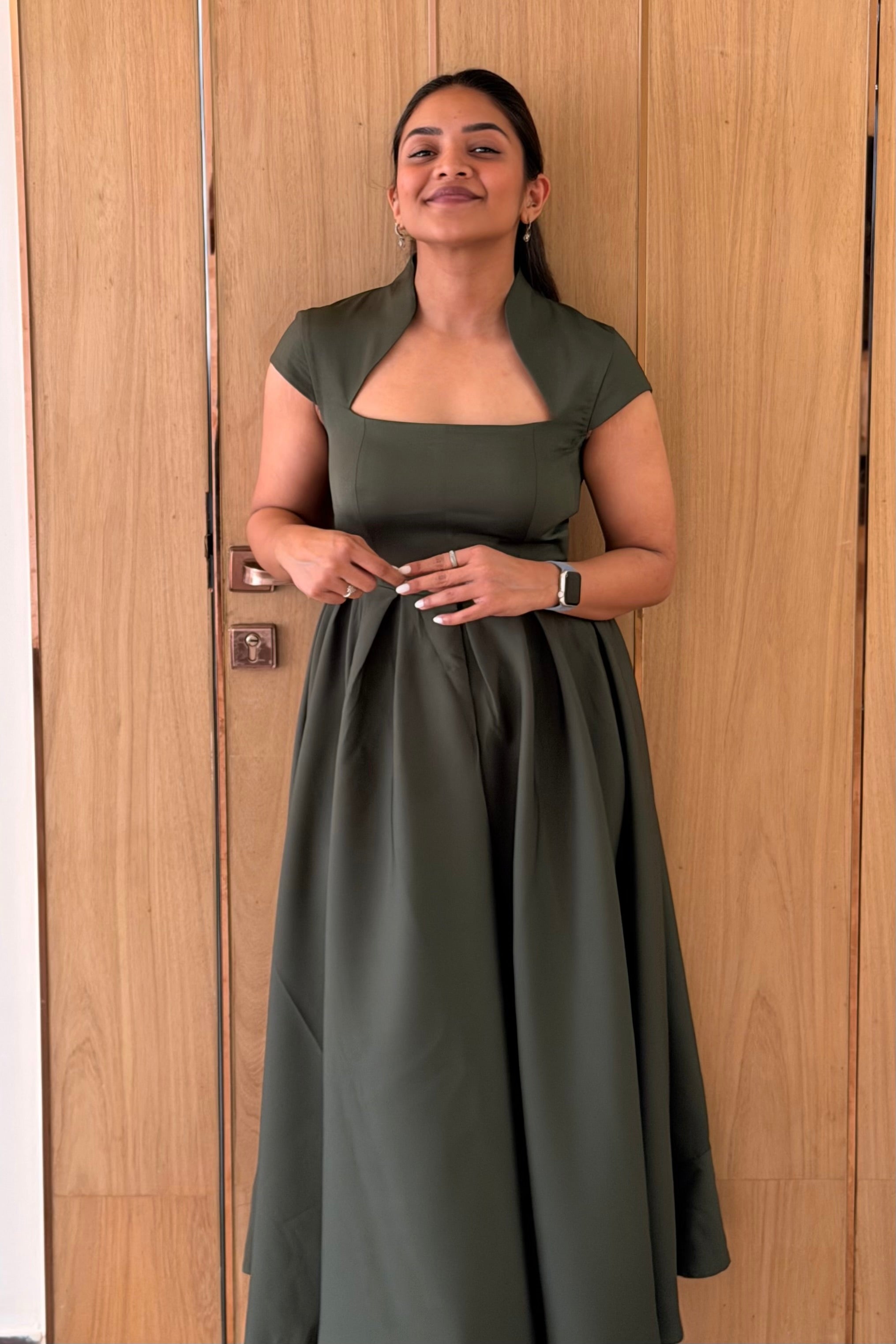 Woman wearing a green dress standing against a wooden door.