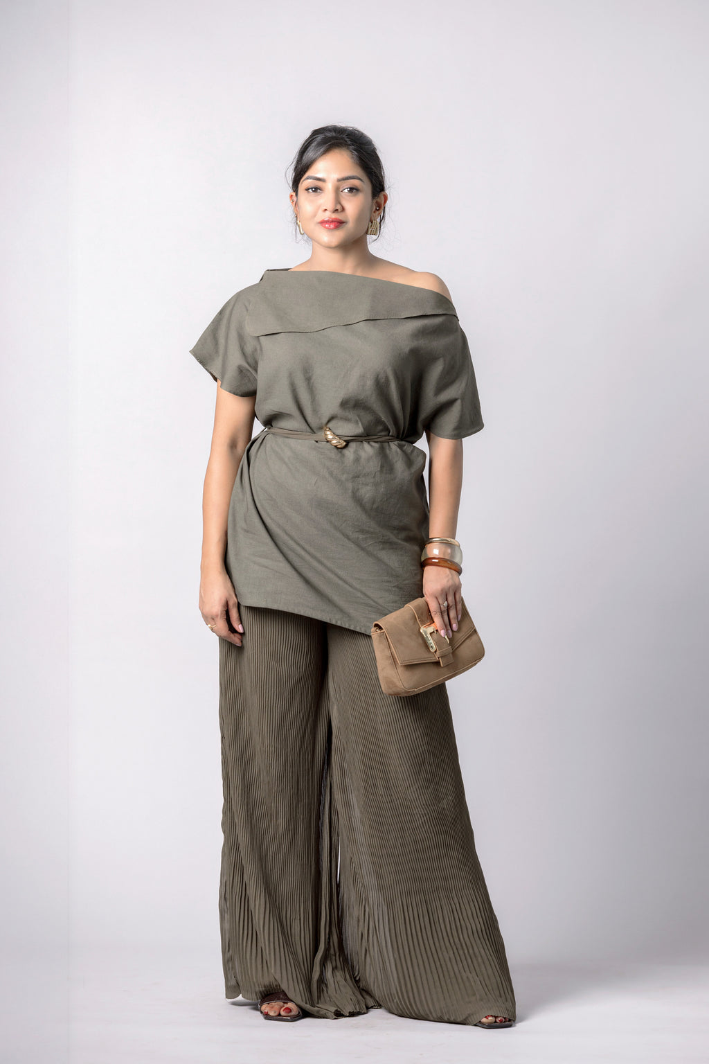 Woman wearing olive asymmetric top with pleated wide-leg pants