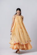 Model wearing a peach layered halter-neck dress with flared hem