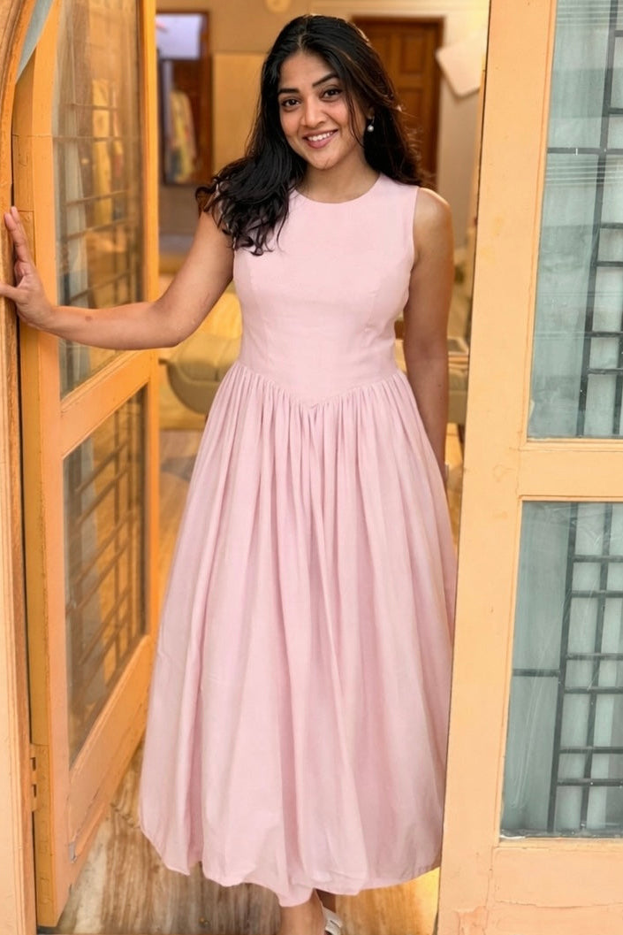 Woman in a pink dress standing in front of a glass door.