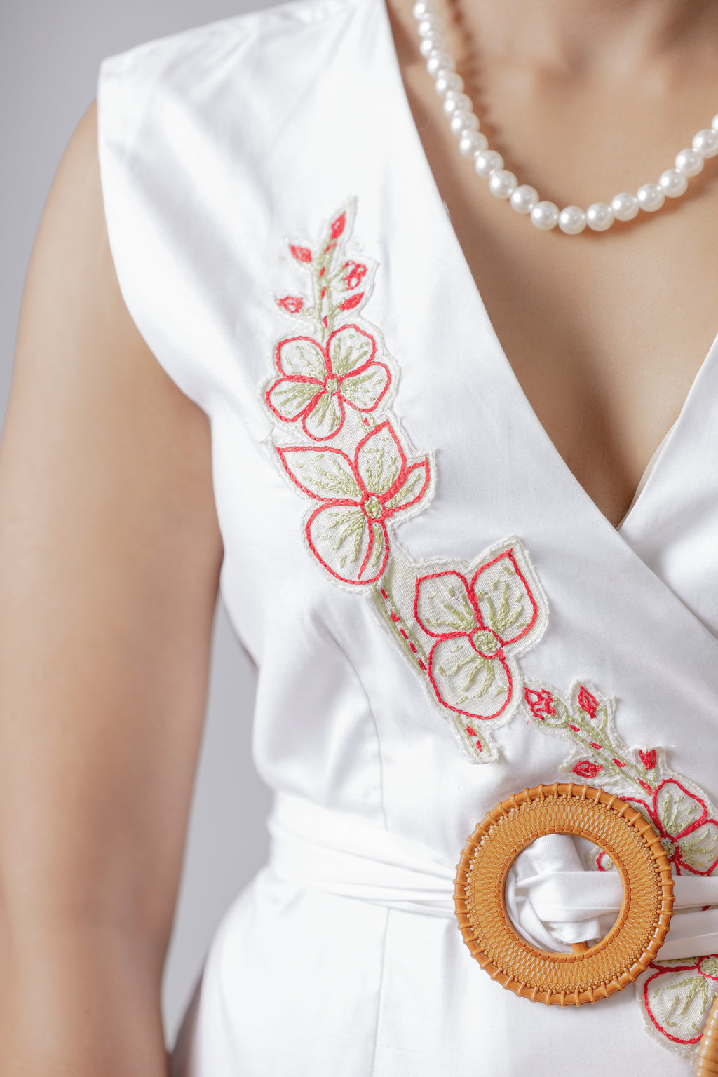 Close-up of floral hand-embroidery and woven belt on white wrap top